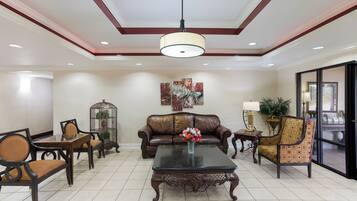 A spacious living area with a leather sofa, a coffee table, and a chandelier.