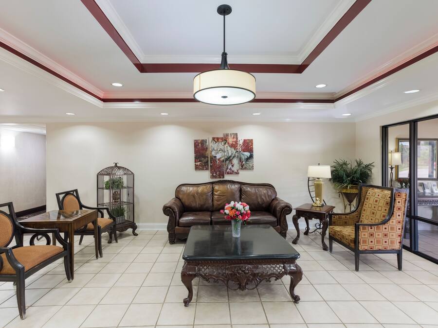 A spacious living area with a leather sofa, a coffee table, and a chandelier.