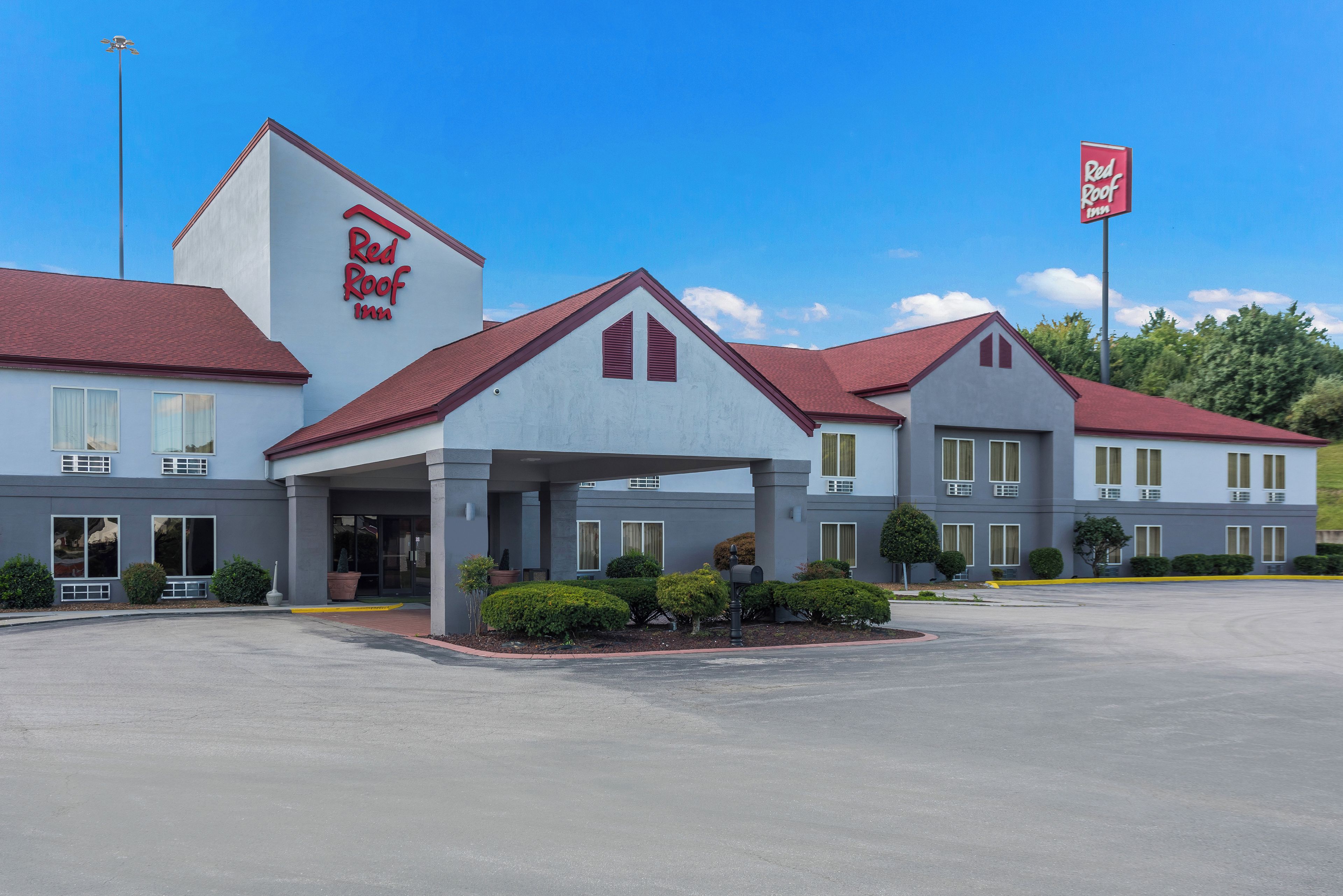 Un hotel Red Roof Inn con un diseño arquitectónico moderno, que cuenta con una entrada cubierta y un estacionamiento.