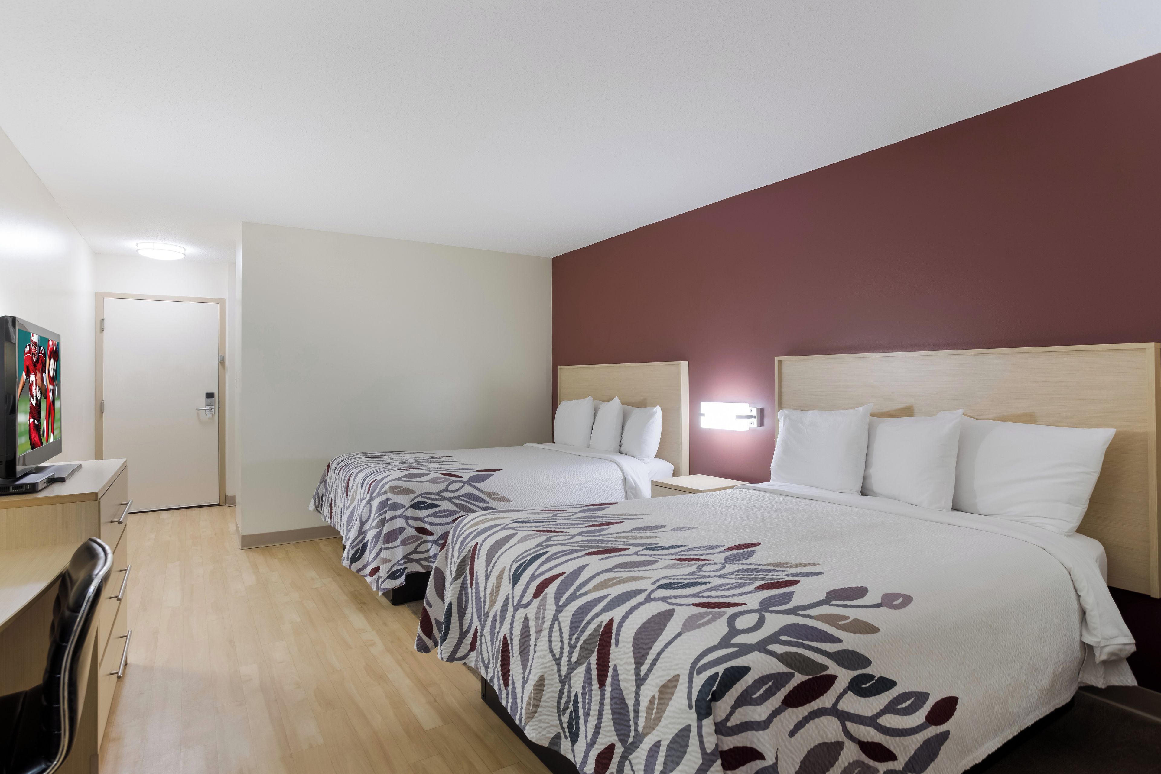 Habitación de hotel con dos camas, un escritorio y un televisor.