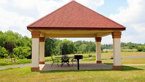 Ein Pavillon mit einem Ziegeldach, einem Tisch und Stühlen auf einer Wiese.