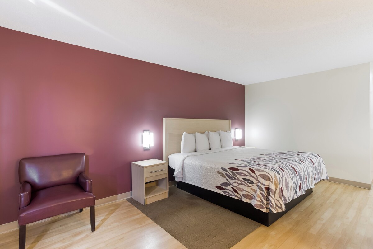 A bedroom with a bed, nightstand, and chair.