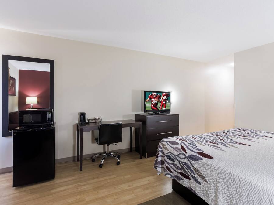 Habitación de hotel con cama, escritorio con silla, televisor, microondas y cafetera.