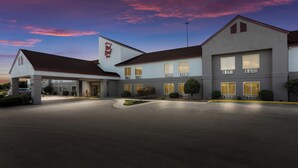 Ein Hotel mit überdachter Eingangsparte, zahlreichen Fenstern und einem gut beleuchteten Parkplatz.