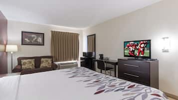 Une chambre d’hôtel avec un lit, un bureau, une télévision et une fenêtre avec des rideaux.