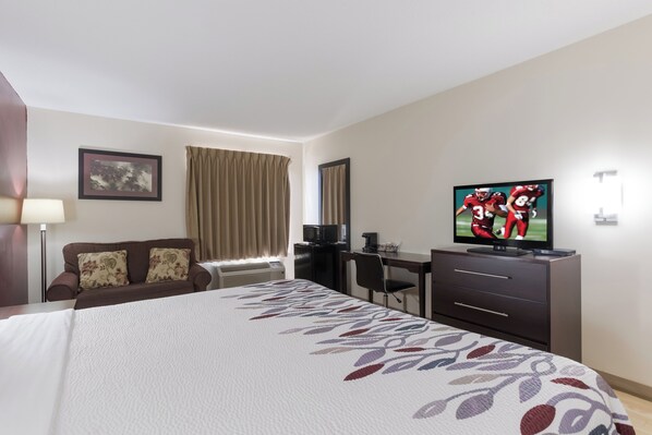 A hotel room with a bed, a desk, a television, and a window with curtains.