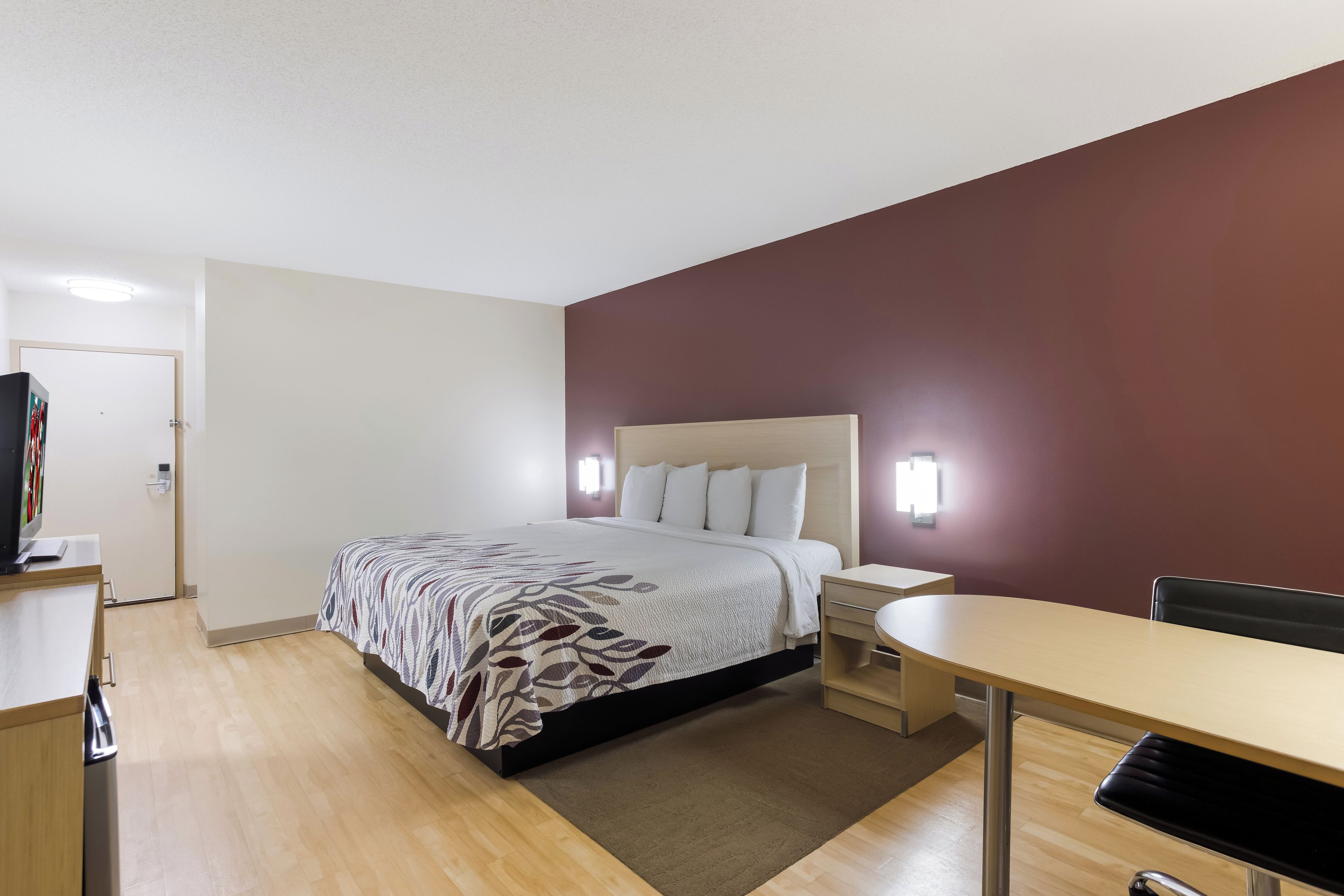 Una habitación de hotel con cama, mesita de noche, escritorio y silla.