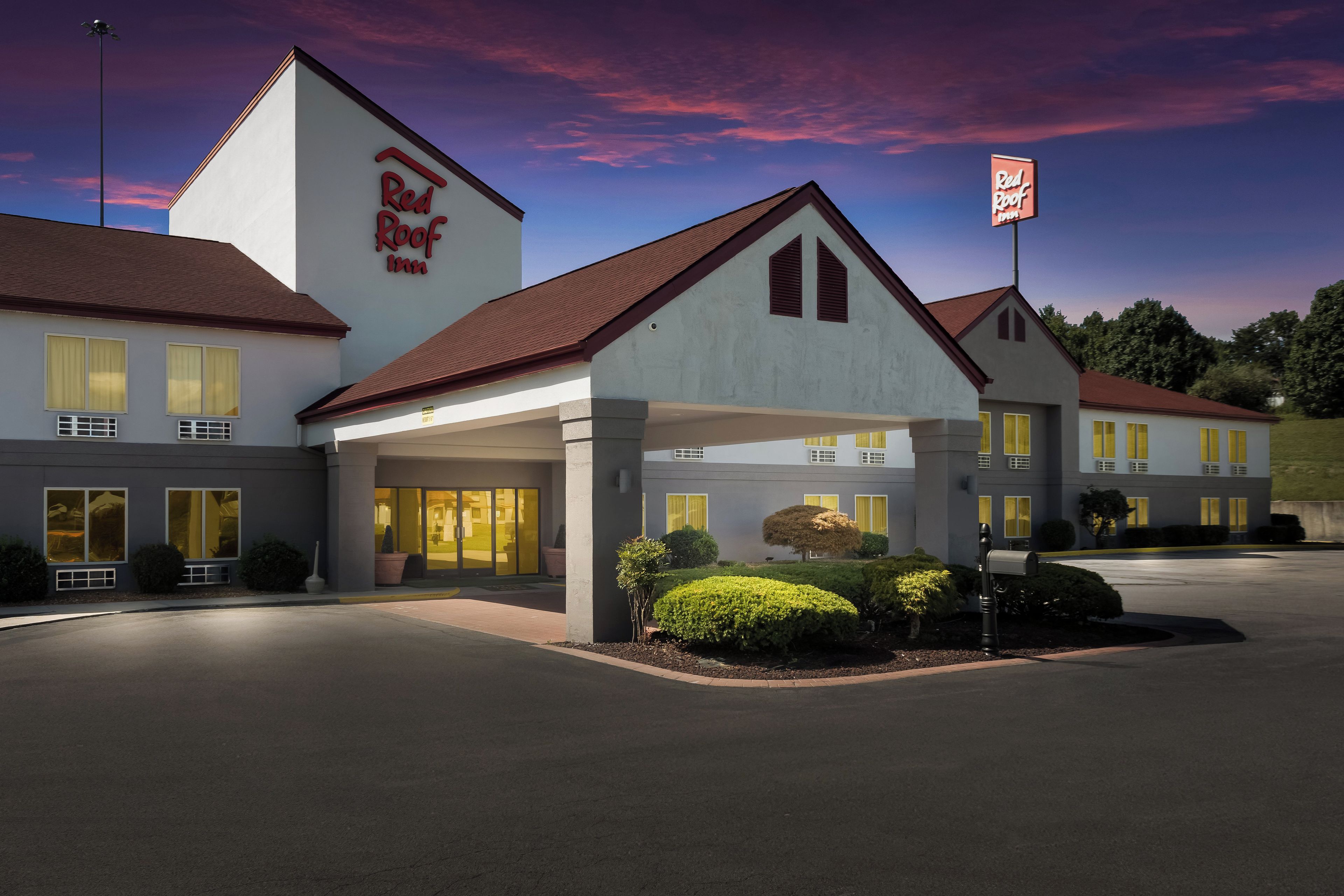 Un Red Roof Inn con un edificio de dos pisos, un acceso cubierto y un estacionamiento.