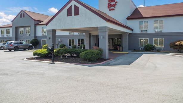 Un hôtel Red Roof Inn doté d’une entrée abritée, de nombreuses fenêtres et d’un parking.