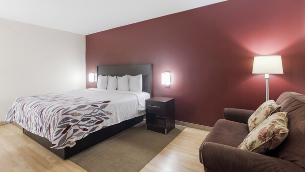 Ein Hotelzimmer mit Bett, Nachttisch, Lampe und einer Sitzecke.