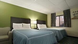A hotel room with two beds, a sofa, a window with curtains, and a coat rack.