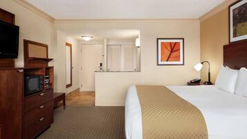 A hotel room with a bed, a TV, a desk, and a bathroom visible through an open door.