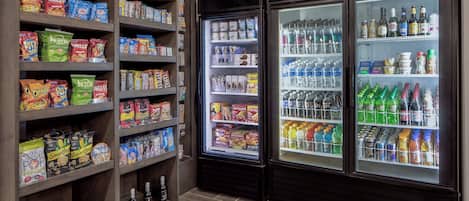 A snack and beverage section with shelves stocked with various snacks and a refrigerated display case with bottled water and drinks.