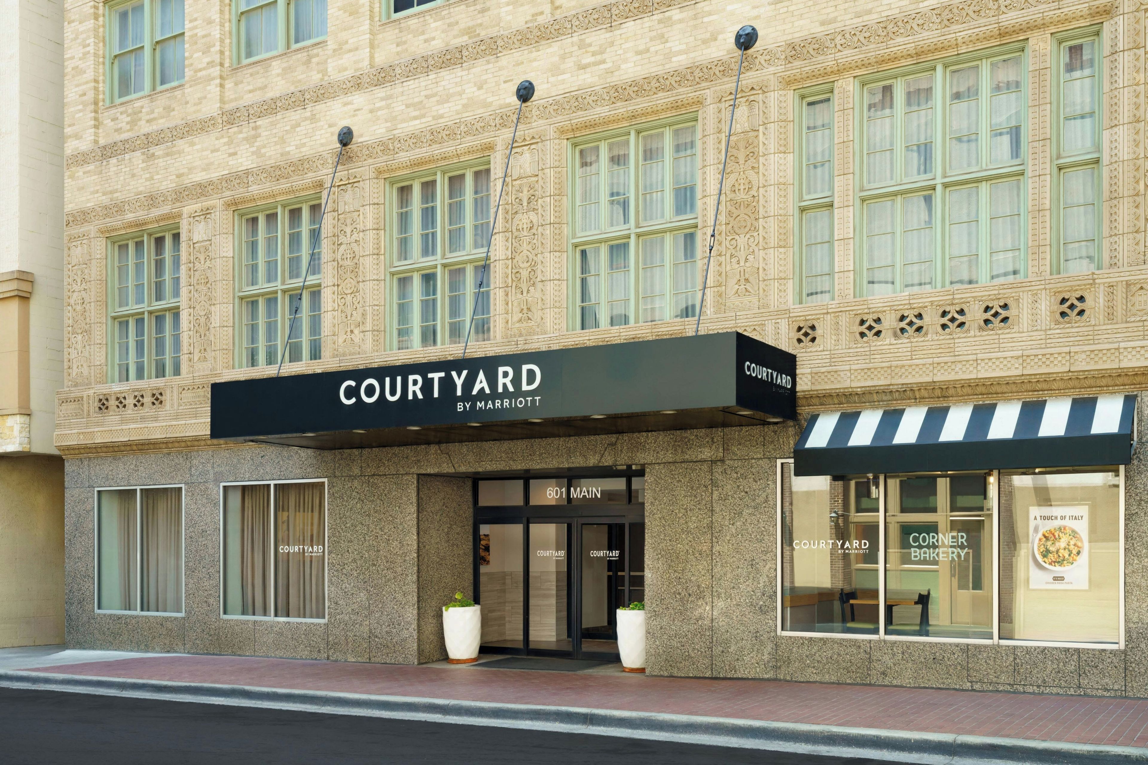 A Courtyard by Marriott hotel facade with a black awning, large windows, and a corner entrance.