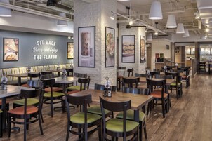 A restaurant interior with wooden tables and chairs, framed artwork on the walls, and a sign that reads "SIT BACK Relax and Enjoy THE FLAVOR".