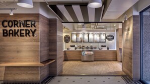 L’intérieur d’une boulangerie, avec un comptoir en bois, des panneaux affichant le menu et un sol à motifs.