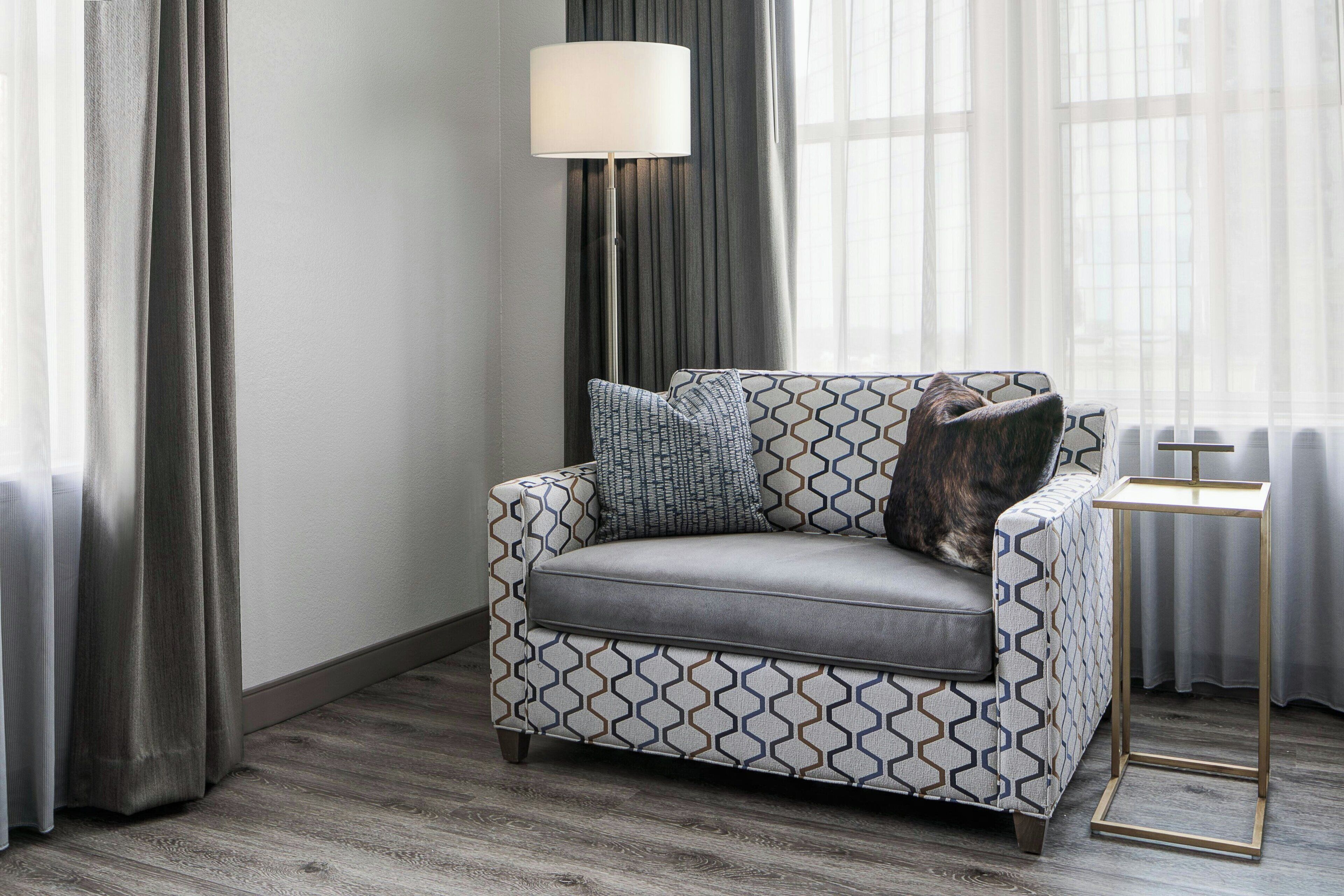 A modern living room with a patterned sofa, a floor lamp, and a small side table.