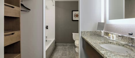 A modern bathroom with a built-in shower, a vanity with a sink, and a wooden shelving unit.