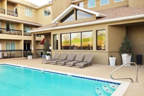 Una piscina al aire libre, sillones reclinables de piscina