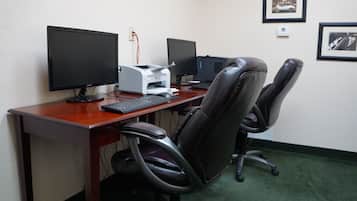 A workspace with two monitors, a keyboard, a printer, and a leather office chair.
