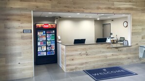 A reception area with a Coca-Cola refrigerator, a welcome mat, and a clock on the wall. - Country Inn & Suites by Radisson, Fort Worth West l-30 NAS JRB (Fort Worth)