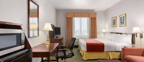 A hotel room with a bed, desk, chair, television, and a microwave.