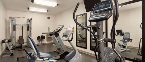 Ein Fitnessstudio mit Cardiogeräten, Gewichten und Spiegeln.