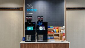 A coffee station with two coffee machines and a sign that reads "MUST HAVE COFFEE."
