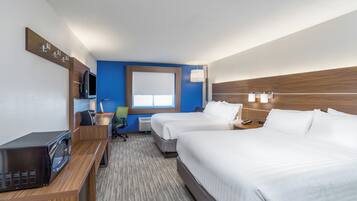 A hotel room with two beds, a desk, a chair, a television, and a window.