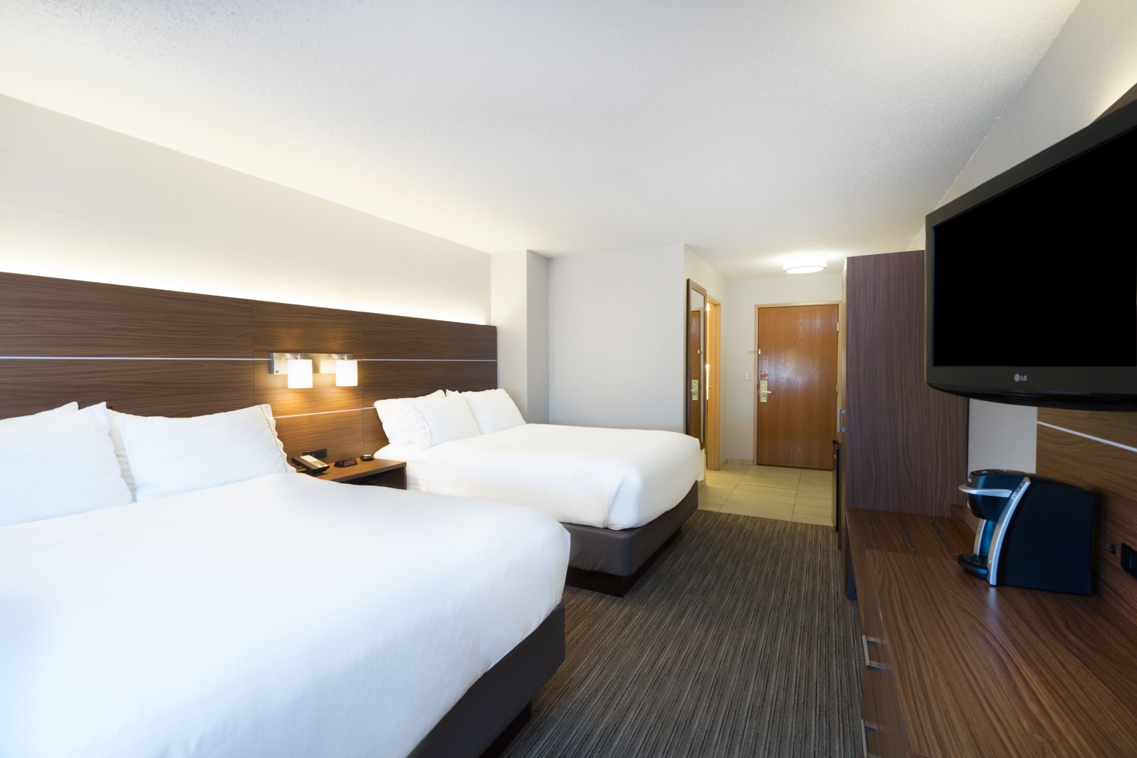 Habitación de hotel con dos camas, televisión y minibar.