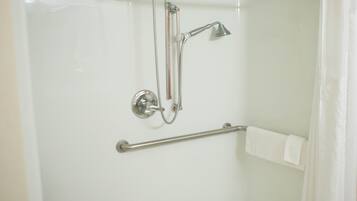 A shower with a handheld showerhead, a wall-mounted faucet, and a grab bar.