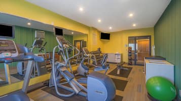A fitness center with cardio machines, free weights, and a mirrored wall.