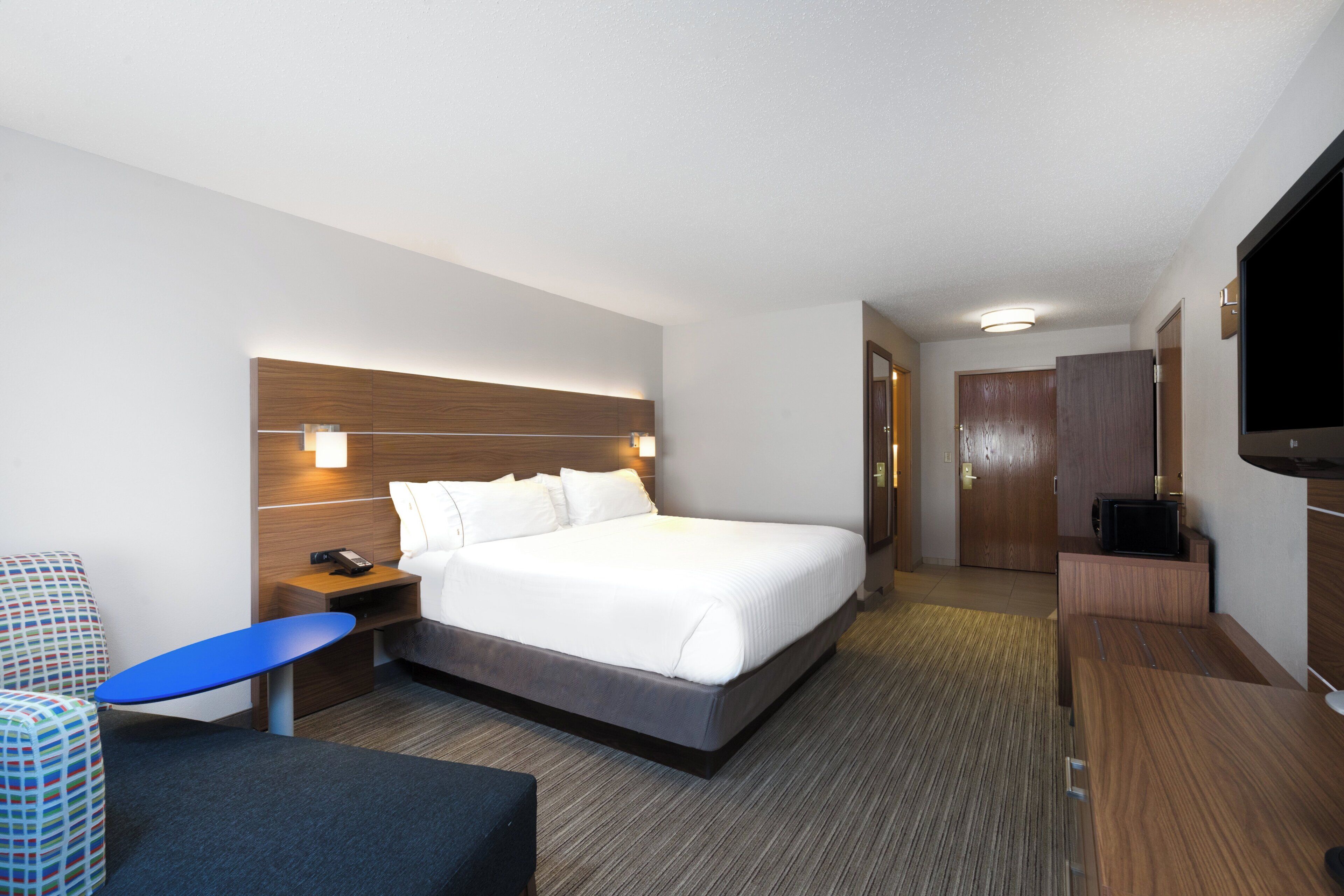 Une chambre d’hôtel comprenant un lit, une table de chevet, une télévision et un bureau avec une chaise.