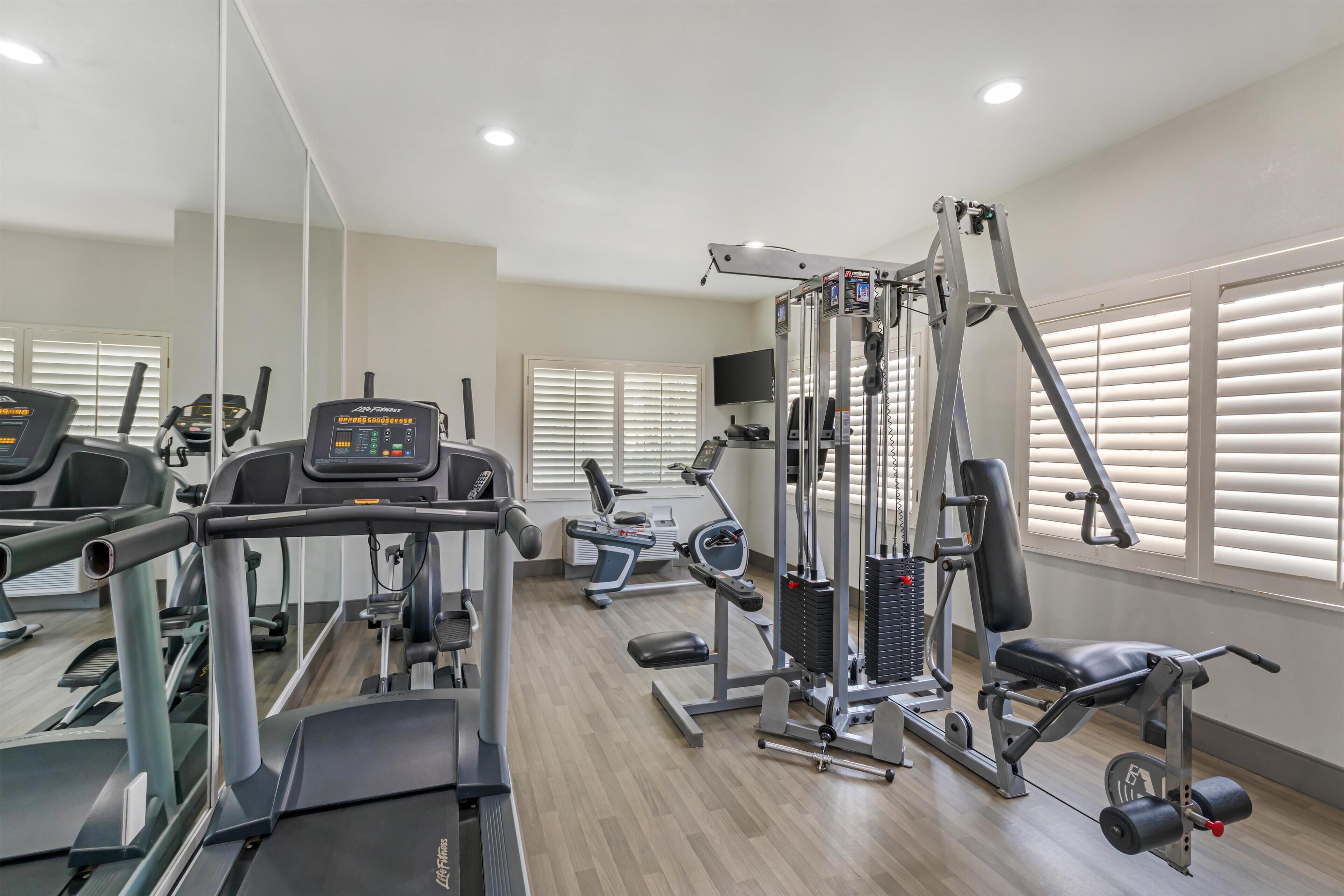 A gym with treadmills, weight machines, and a mirrored wall.