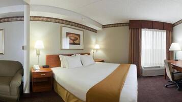 A hotel room with a large bed, two bedside tables, a desk, a chair, and a window with curtains.