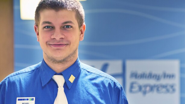 A man in a blue shirt with a name tag reading "MICHAEL" and a white tie. - Holiday Inn Express Hotel & Suites Colby by IHG (Colby)