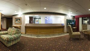 A reception area with a wooden reception desk, a patterned carpet, and several upholstered chairs.