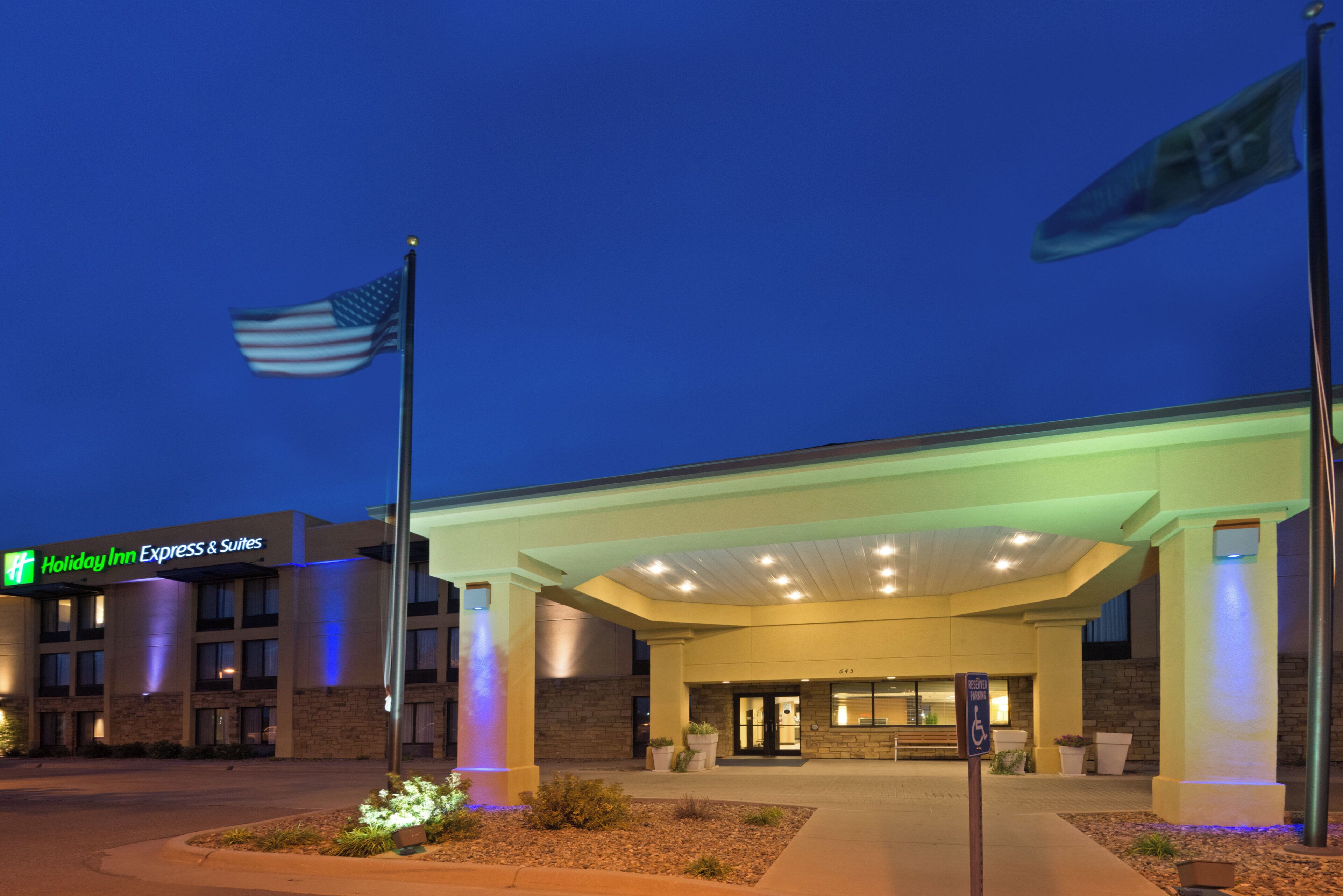 A Holiday Inn Express & Suites building at dusk with an American flag on a flagpole.