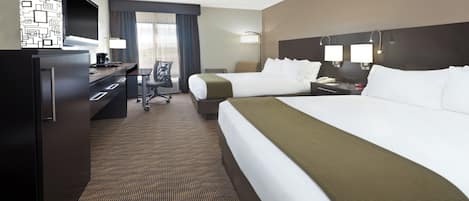 A hotel room with two beds, a desk, a chair, and a minibar.