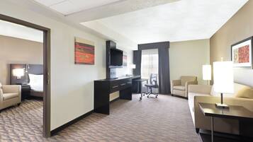 A hotel room with a bed, a desk, a television, a chair, and a lamp.