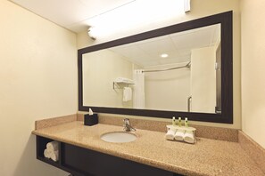 A bathroom with a sink, mirror, towel rack, and a shelf with toiletries. - Holiday Inn Express Hotel & Suites Colby by IHG (Colby)