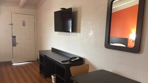 Ein Zimmer mit Schreibtisch, Stühlen, einem Flachbildfernseher an der Wand und einer Tür.
