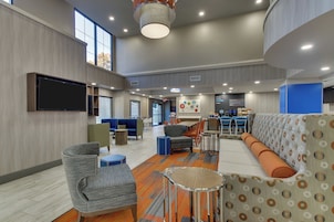 A modern lounge area with seating, a flat-screen TV, and a coffee station.