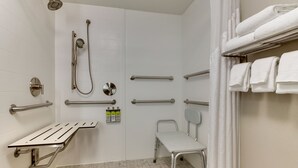 A modern bathroom with a shower, grab bars, a bench, and a towel rack. - Holiday Inn Express & Suites Atlanta N-Perimeter Mall Area by IHG (Atlanta)