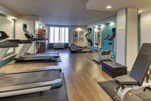 Une salle de sport équipée de tapis de course, de vélos d’appartement et d’un appareil d’aviron.