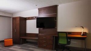 A hotel room with a wooden desk, a green office chair, a television mounted on the wall, and a wardrobe. - Holiday Inn Express & Suites Atlanta N-Perimeter Mall Area by IHG (Atlanta)