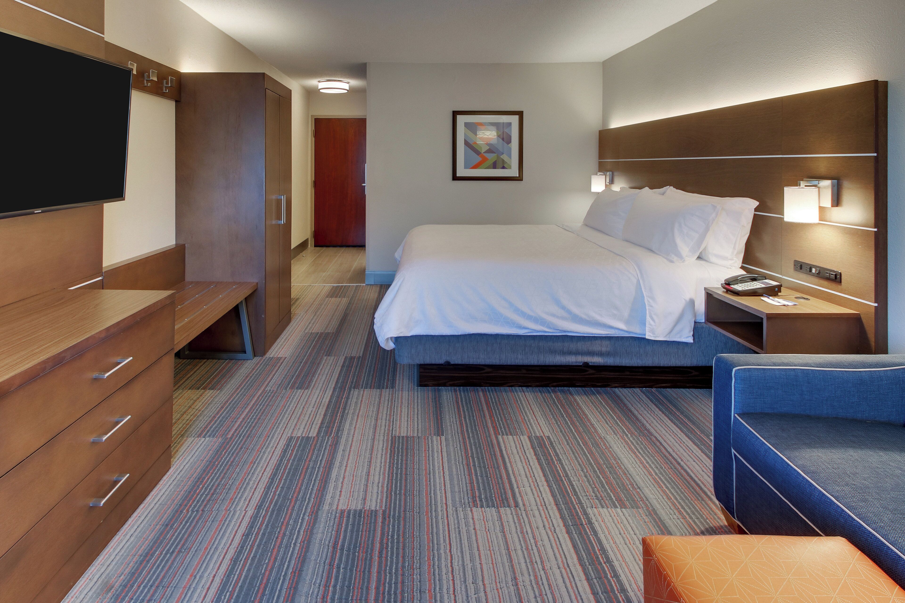 Une chambre d’hôtel comprenant un lit, une télévision, un bureau et un coin salon.