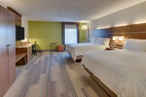 Ein Hotelzimmer mit zwei Betten, einem Schreibtisch mit Stuhl, einem Fernseher und einem Fenster.