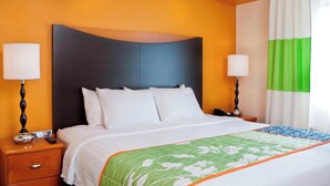 Een hotelkamer met een bed, twee nachtkastjes en een raam met gordijnen.