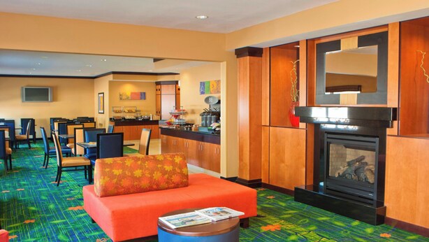 Een hotel lobby met een bank, stoelen, een koffiehoek en een open haard.